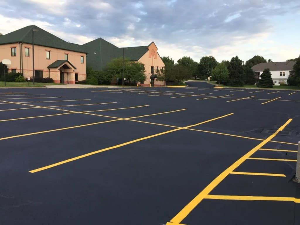 Large freshly seal-coated and striped commercial parking lot with crisp yellow lines at office complex in Linden, NJ